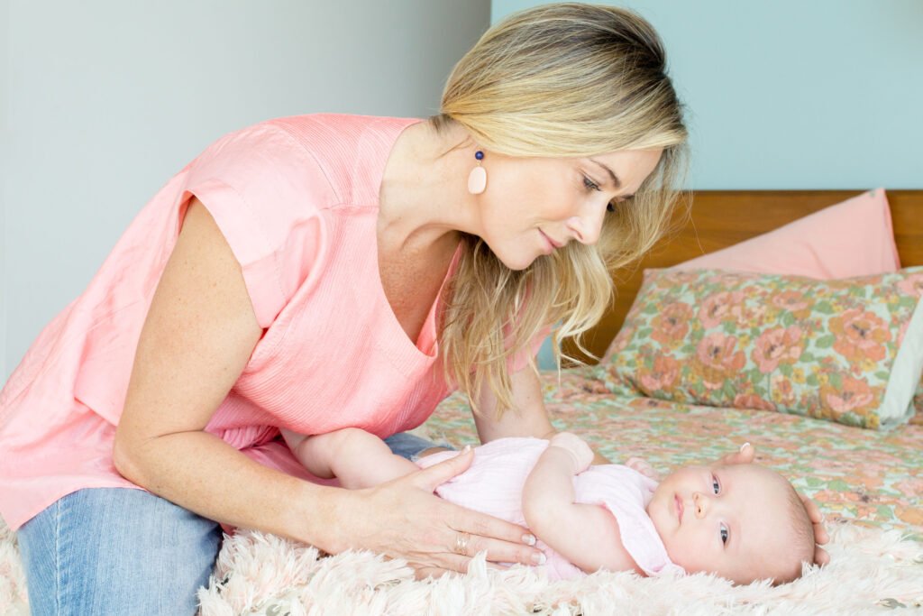 Mother comforting baby on bed while supporting better rest—baby sleep cycles explained through gentle routines