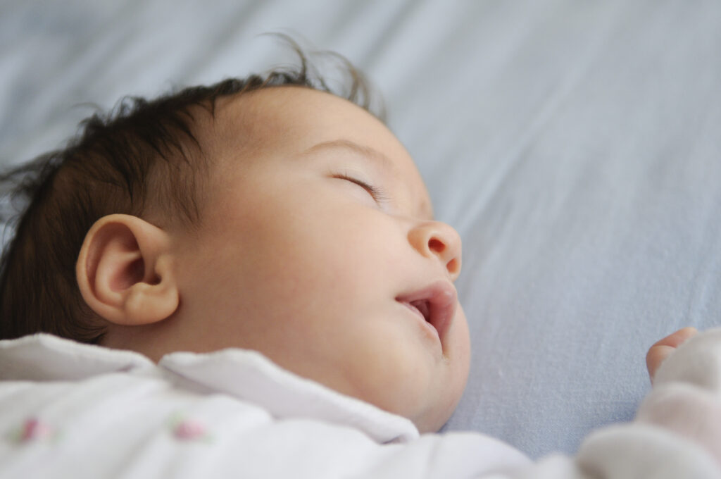 Close-up of sleeping newborn showing baby sleep cycles explained through REM and non-REM patterns