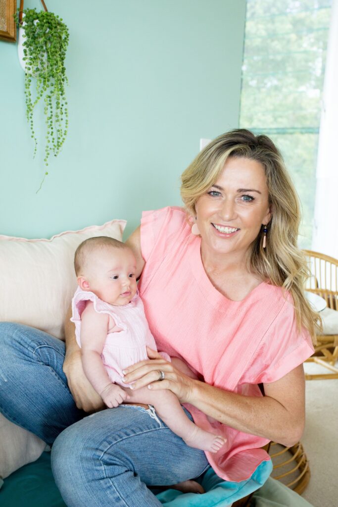 Elaine Harvey providing gentle sleep support as she holds a happy baby in her arms on a cozy couch