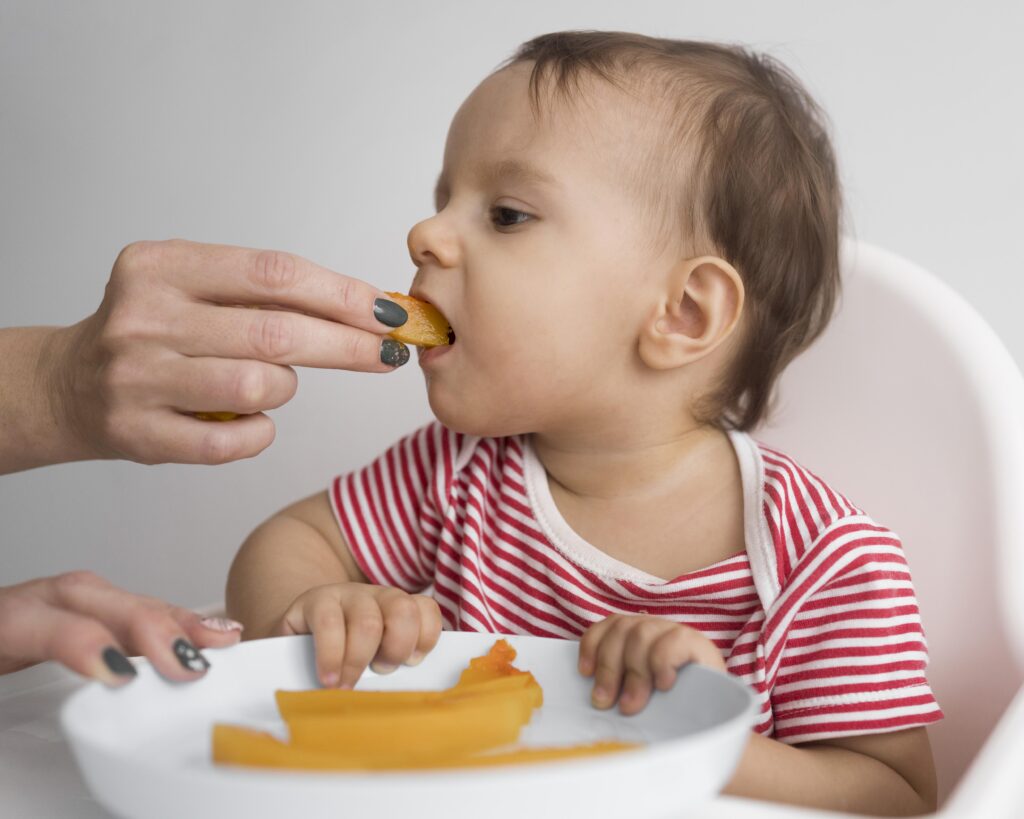 Baby trying soft finger foods like melon as part of a baby-led and spoon-fed solids introduction.