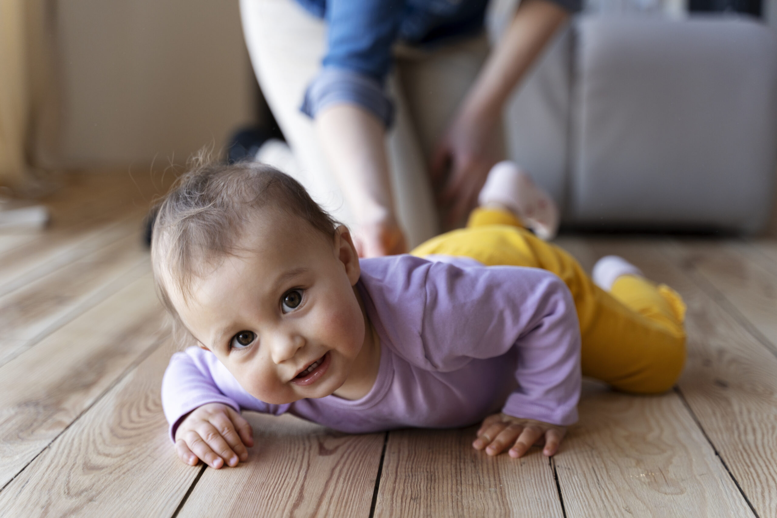Parent pausing while baby fusses on tummy in cot, allowing time to self-settle