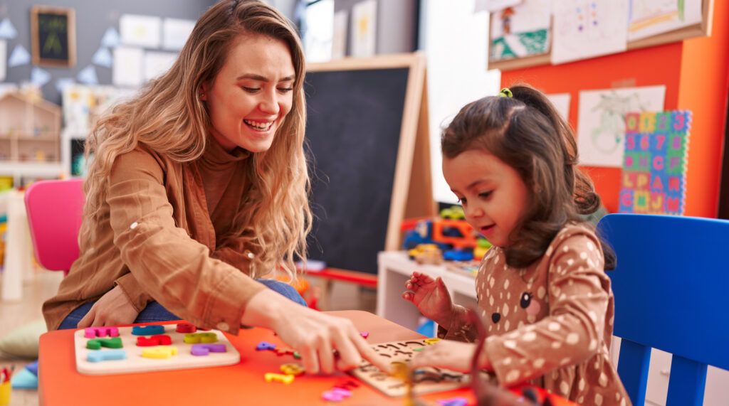 Toddler explores a colourful childcare room with their parent nearby for reassurance during an orientation visit before their first day